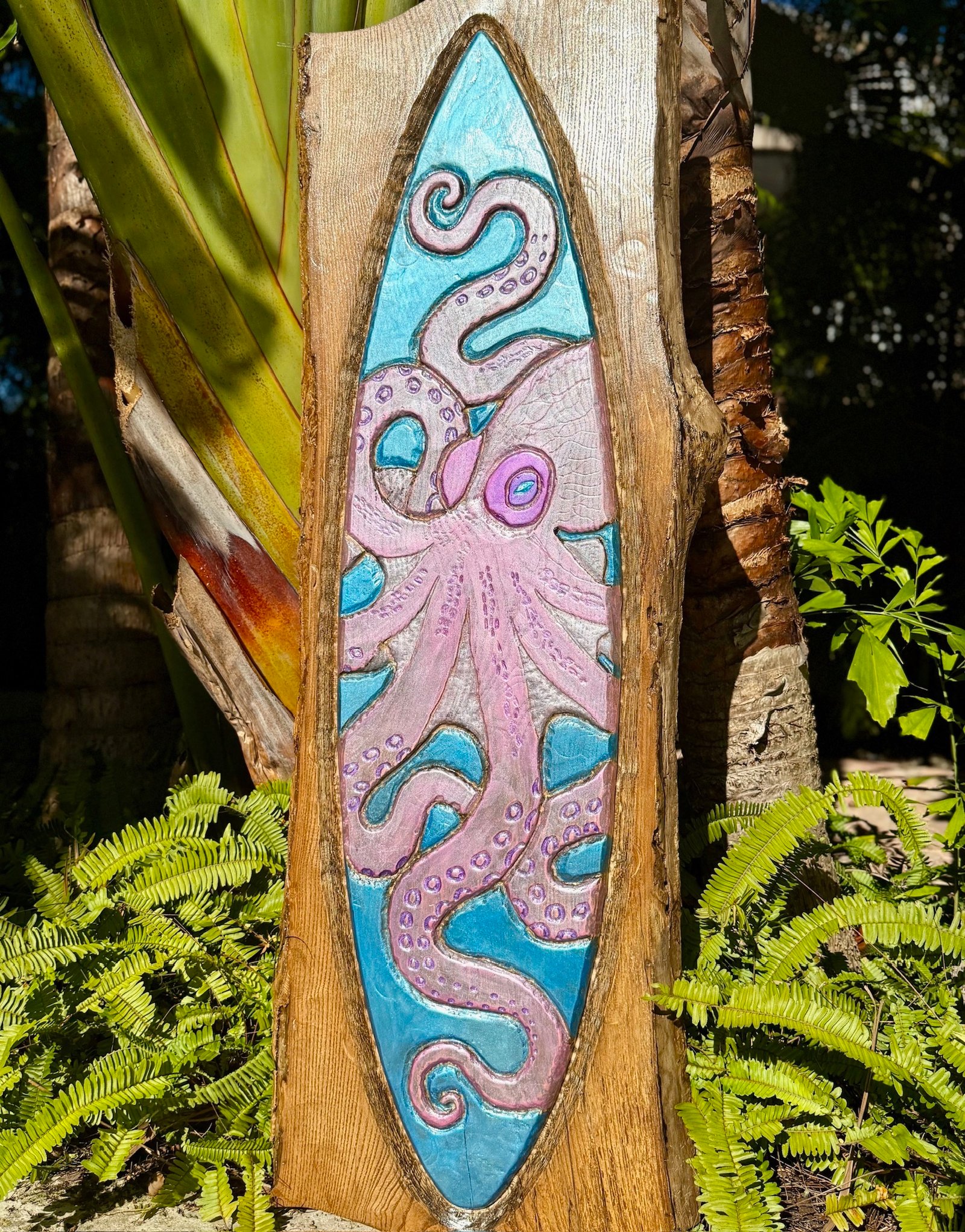 Pearl live-edge wood slab carved with a pink octopus flowing through a turquoise surfboard silhouette
