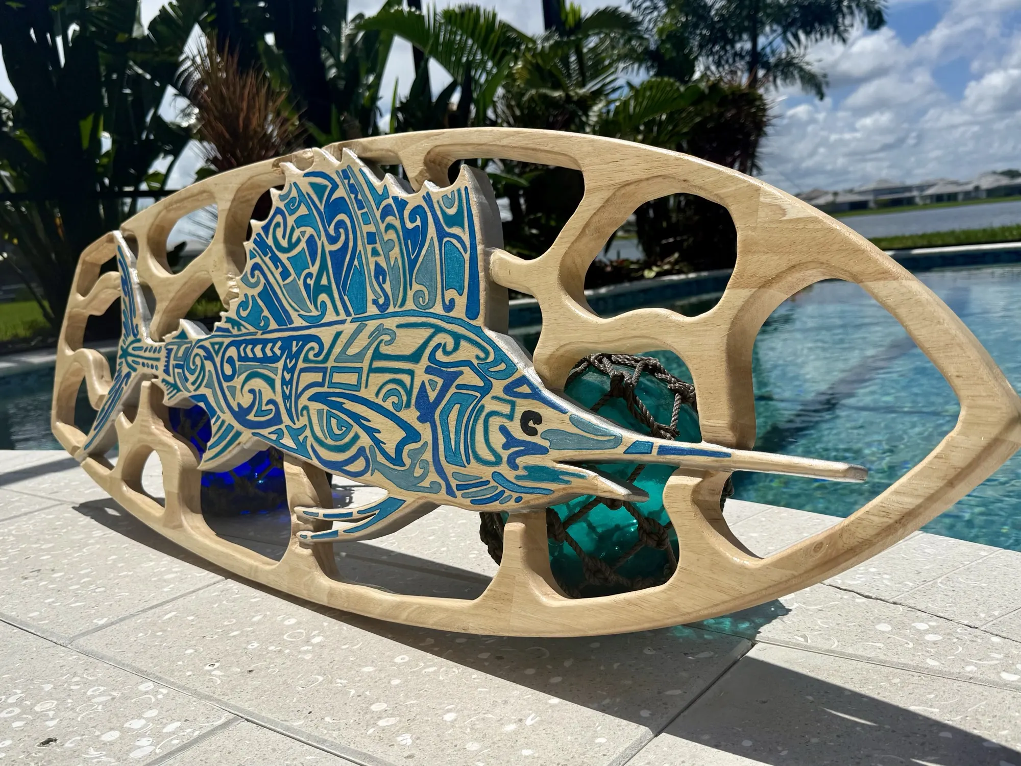 Ocean-blue tribal sailfish within a hand-carved open-frame lattice wooden surfboard
